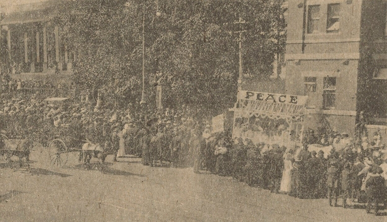 Newspaper clipping showing a march or rally of people holding a sign saying 'peace'.
