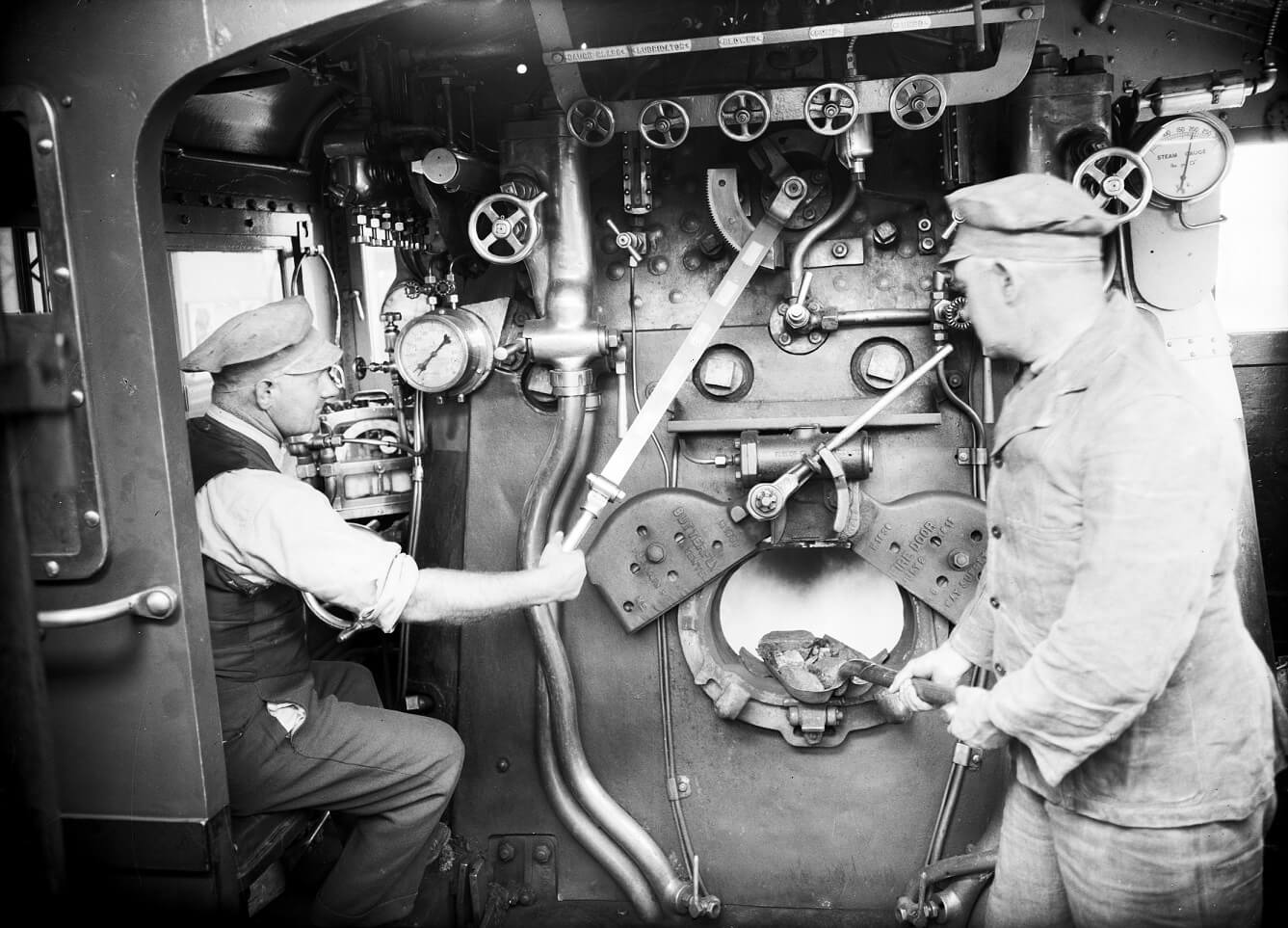 Interior of a S Class steam locomotive cabin Driver at the regulator and fireman shovelling coal into the firebox