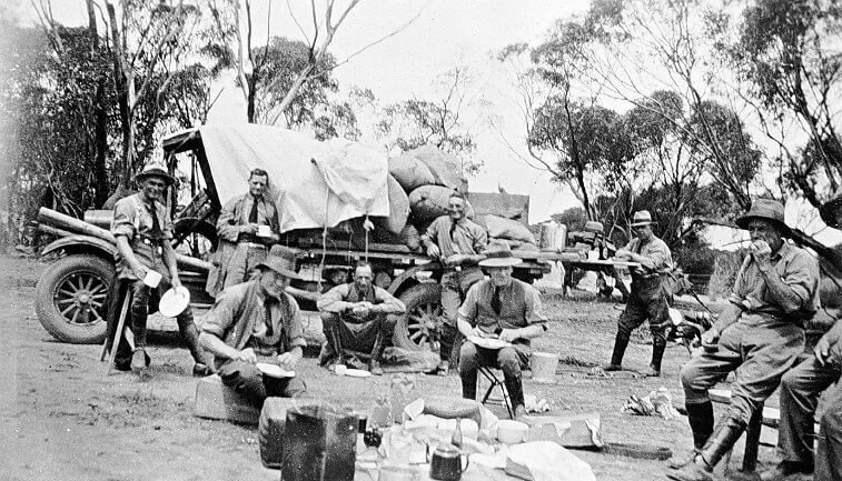 black and white photograph of men who appear to be having a tea break on a farm.