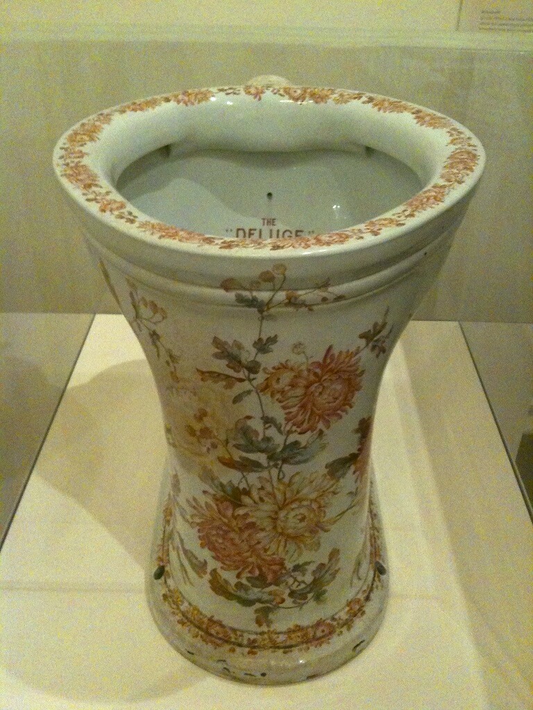 Photograph of an ornate ceramic toilet. It is painted with chrysanthemums in various shades of orange and pink.