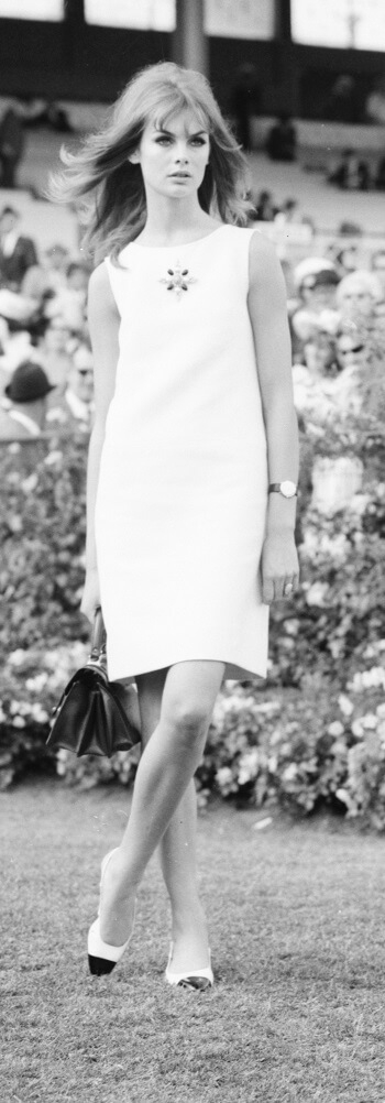 A woman wearing a short white dress poses for the camera.
