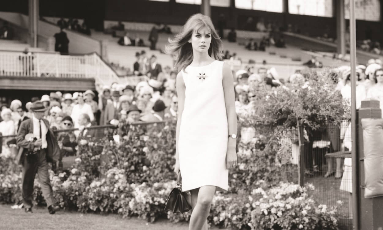 A woman wearing a short white dress poses for the camera.
